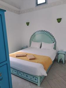 a bedroom with a bed with a green headboard at villa izabelles in Djerba