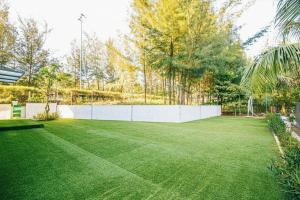a large yard with a white fence and green grass at Sea Villa - FLC Sam Son in Sầm Sơn