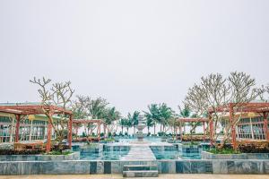 una fontana di fronte a un edificio alberato di The Victoria Resort Sam Son a Sầm Sơn