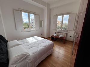 una camera con un letto bianco e due finestre di La Piazzetta ad Avellino