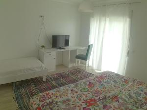 a bedroom with a bed and a desk with a television at Hotel Baleal Spot in Baleal