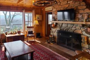sala de estar con chimenea de piedra y TV en Smoky Mountain Vista en Tallassee