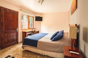 a bedroom with a bed with blue pillows and a desk at Hotel Serena Suite in La Serena