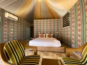 a bedroom with a bed and two chairs at مخيم الانيق in Wadi Rum