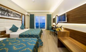 a hotel room with two beds and a desk at Sun Star Resort Hotel in Alanya