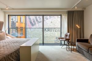 a bedroom with a bed and a couch and a large window at Boutique Hotel Herman K in Copenhagen