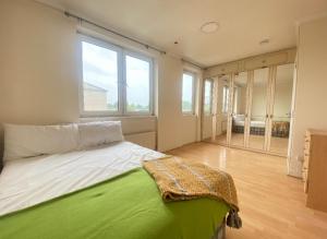 Un dormitorio con una cama verde y blanca y ventanas en Modern Room for Rent in Vibrant E14: Your Urban Sanctuary Awaits! en Londres