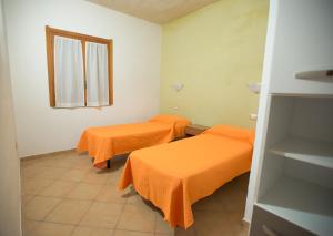 2 camas en una habitación con sábanas de color naranja en Hotel Club Baia delle Mimose, en Badesi