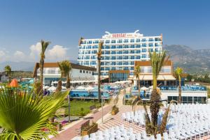 a hotel with white tables and chairs and palm trees at Sun Star Resort Hotel in Alanya