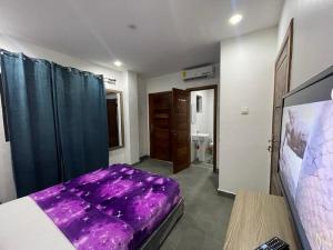 a bedroom with a purple bed and a bathroom at Am apartment in Accra