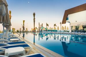 a pool with chairs and palm trees and a building at Sun Star Resort Hotel in Alanya +33 photos