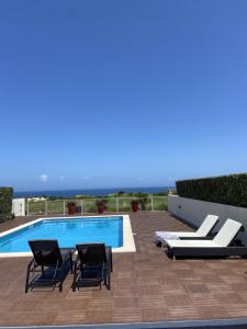 una piscina con 2 sillas y una piscina en Fantástica V3 Vista Mar & Golfe Praia Del Rey, Óbidos, en Amoreira