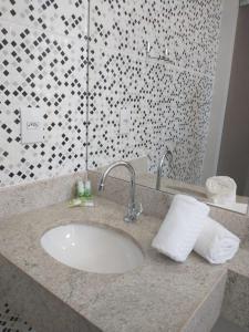 a bathroom counter with a sink and a shower at Hotel Cabana in Caetanópolis
