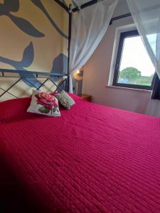 Schlafzimmer mit einem Bett mit einer roten Tagesdecke und einem Fenster in der Unterkunft Agriturismo La Buona Compagnia in Iesi