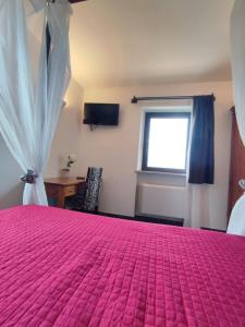ein Schlafzimmer mit einem rosa Bett und einem Fenster in der Unterkunft Agriturismo La Buona Compagnia in Iesi