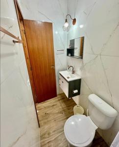 a white bathroom with a toilet and a sink at Apartamentos - Estúdios in São José