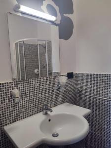 La salle de bains est pourvue d'un lavabo blanc et d'un miroir. dans l'établissement Agriturismo La Buona Compagnia, à Jesi