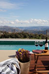 a table with two glasses of wine next to a pool at Casa do Santo - Wine & Tourism in Provesende