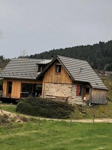 ein Holzhaus auf einem Hügel mit einem Feld in der Unterkunft Au croque nature in Soultzeren