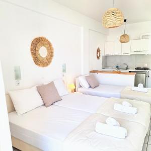 two white beds in a room with a kitchen at Villa Thalassa Apartments in Pefkohori