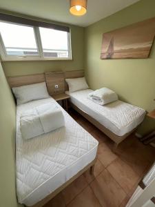 Dos camas en una habitación con dos ventanas. en 226, Sundowner Holiday Park, Hemsby - Two bed detached chalet, sleeps four, bed linen and towels included plus free WiFi - Pets welcome, en Hemsby