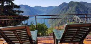 two chairs on a balcony with a view of mountains at VillaMarinaPigra Lake View Apartments in Pigra