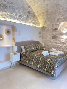 1 dormitorio con cama y pared de piedra en Eureka luxury room, en Ostuni