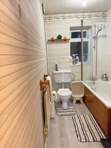 a bathroom with a toilet and a tub and a sink at Two Double Bedroom Maisonette with rear garden. 
