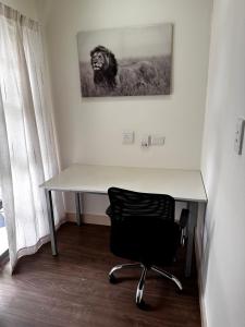 uma secretária com uma cadeira e uma fotografia de um leão em Nosu Modern Apartments Rivonia em Joanesburgo