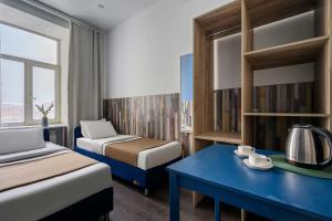 a hotel room with two beds and a blue table at Отель РиверСайд Невский in Saint Petersburg