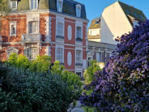 Une rangée de bâtiments avec des fleurs violettes devant eux dans l'établissement We Sea, à Deauville