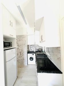une cuisine avec des placards blancs et un comptoir noir dans l'établissement Cosy Sunny One Bedroom Apartment, à Paphos