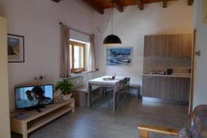 a living room with a tv and a table and a kitchen at Dolomitissime Holiday Homes Marmolada in Rocca Pietore