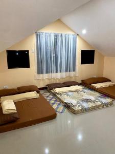 two beds in a room with a large window at TopBudz Hostel Panagsama Moalboal in Moalboal