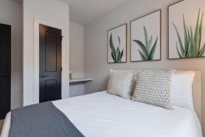 Hygge - Odyssey - Heart of Midtown في ناشفيل: غرفة نوم مع سرير أبيض مع لوحات على الحائط