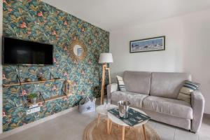 a living room with a couch and a wall mural at Appartement dans résidence calme à 100m de la plage in Saint-Brévin-lʼOcéan