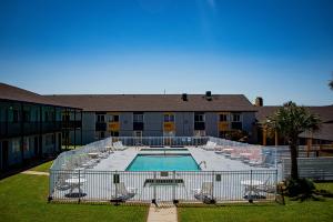 a swimming pool with chairs and a building at Super 8 by Wyndham Biloxi in Biloxi