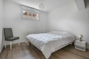 a white bedroom with a bed and a chair at Appartement dans résidence calme à 100m de la plage in Saint-Brévin-lʼOcéan