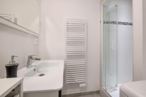 a white bathroom with a sink and a shower at Appartement dans résidence calme à 100m de la plage in Saint-Brévin-lʼOcéan +15 photos