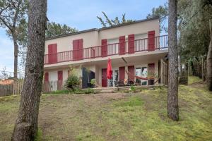 a house with red doors and a balcony at Appartement dans résidence calme à 100m de la plage in Saint-Brévin-lʼOcéan