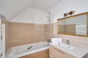 a bathroom with a tub and a sink and a mirror at À 700m de la plage, charmante maison pour 6 in Kersuluan