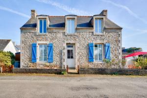 a stone house with blue shutters and a red umbrella at À 700m de la plage, charmante maison pour 6 in Kersuluan