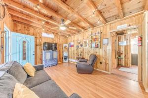 ein Wohnzimmer mit einem Sofa und einem TV sowie Holzwänden in der Unterkunft Ruidoso Cabin with Hot Tub - 2 Mi to Grindstone Lake in Ruidoso