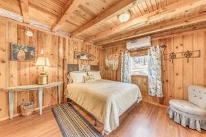 Schlafzimmer mit Holzwänden, einem Bett und einem Stuhl in der Unterkunft Ruidoso Cabin with Hot Tub - 2 Mi to Grindstone Lake in Ruidoso