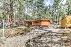 eine Hütte im Wald neben einer Straße in der Unterkunft Ruidoso Cabin with Hot Tub - 2 Mi to Grindstone Lake in Ruidoso