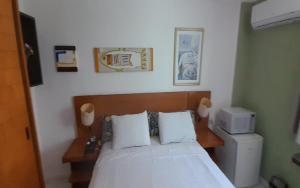 1 dormitorio con cama con colcha blanca e impresora en Sonia Flats Natal - No Apart Hotel Ponta Negra Beach, en Natal