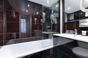 a bathroom with a tub and a sink and a toilet at Hôtel Du Leman in Paris +21 photos