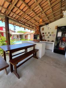 a large kitchen with a table and a refrigerator at Vila Uryah in Caraíva