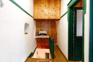 Cette chambre est dotée de murs en bois et d'une porte verte. dans l'établissement GuestHouse 1805, à Gjirokastër