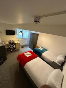 Cette chambre comprend deux lits et un bureau. dans l'établissement Macclesfield Lodge, à Macclesfield